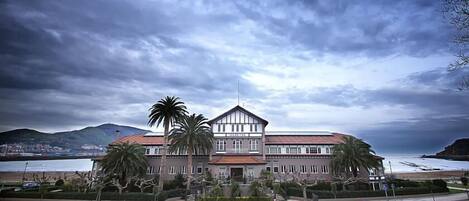 A large, two-story building with a symmetrical facade, a central entrance, and a flat roof.