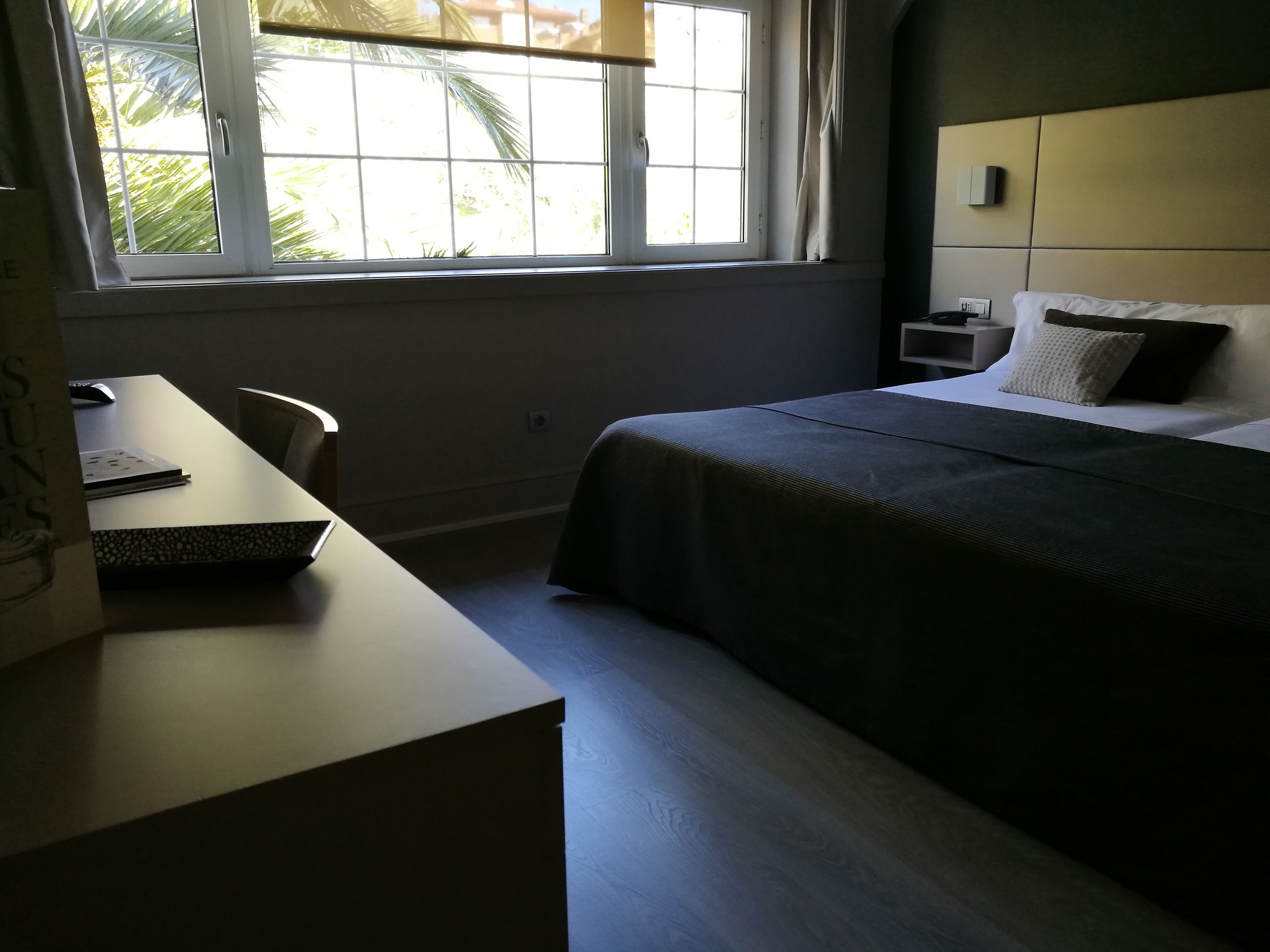 Un dormitorio con cama, mesita de noche y escritorio con silla.