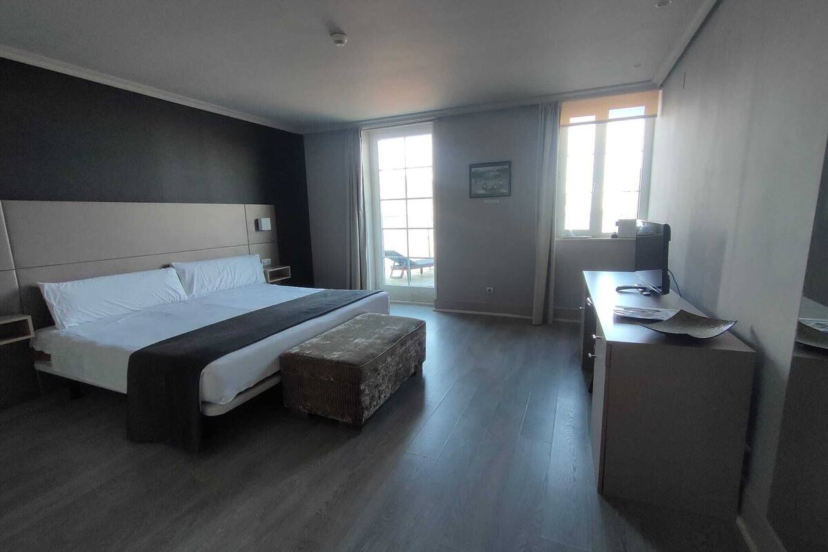 A modern hotel room with a large bed, a desk, and a chair.