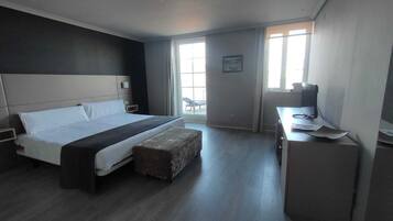 A modern hotel room with a large bed, a desk, and a chair.
