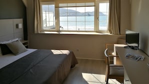 A hotel room with a bed, a desk, and a large window with a view of the sea. - Hotel Igeretxe (Getxo)