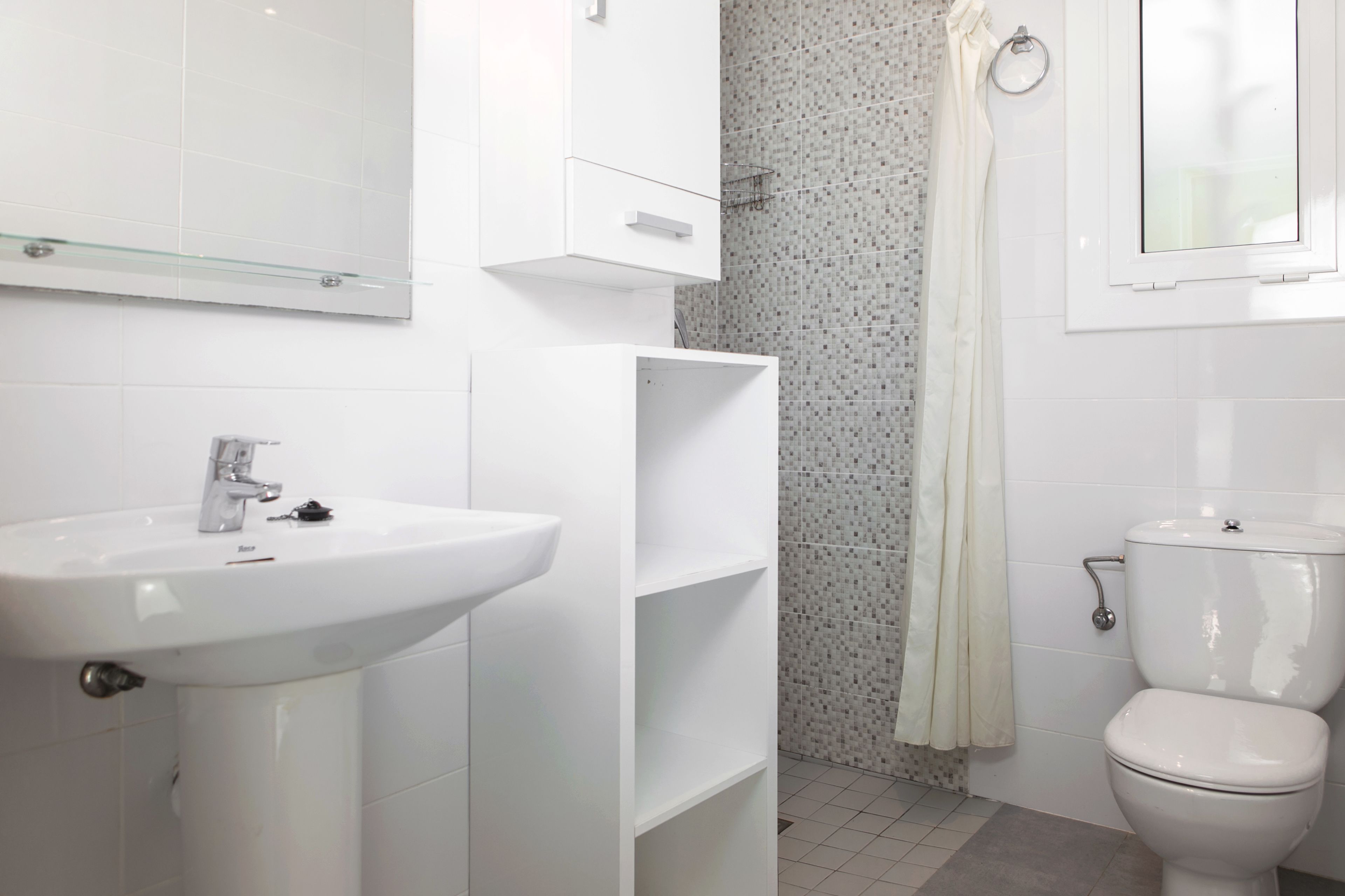 A modern bathroom with a white sink, a toilet, and a shower area.