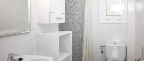 Une salle de bain moderne avec un lavabo blanc, des toilettes et un rideau de douche.