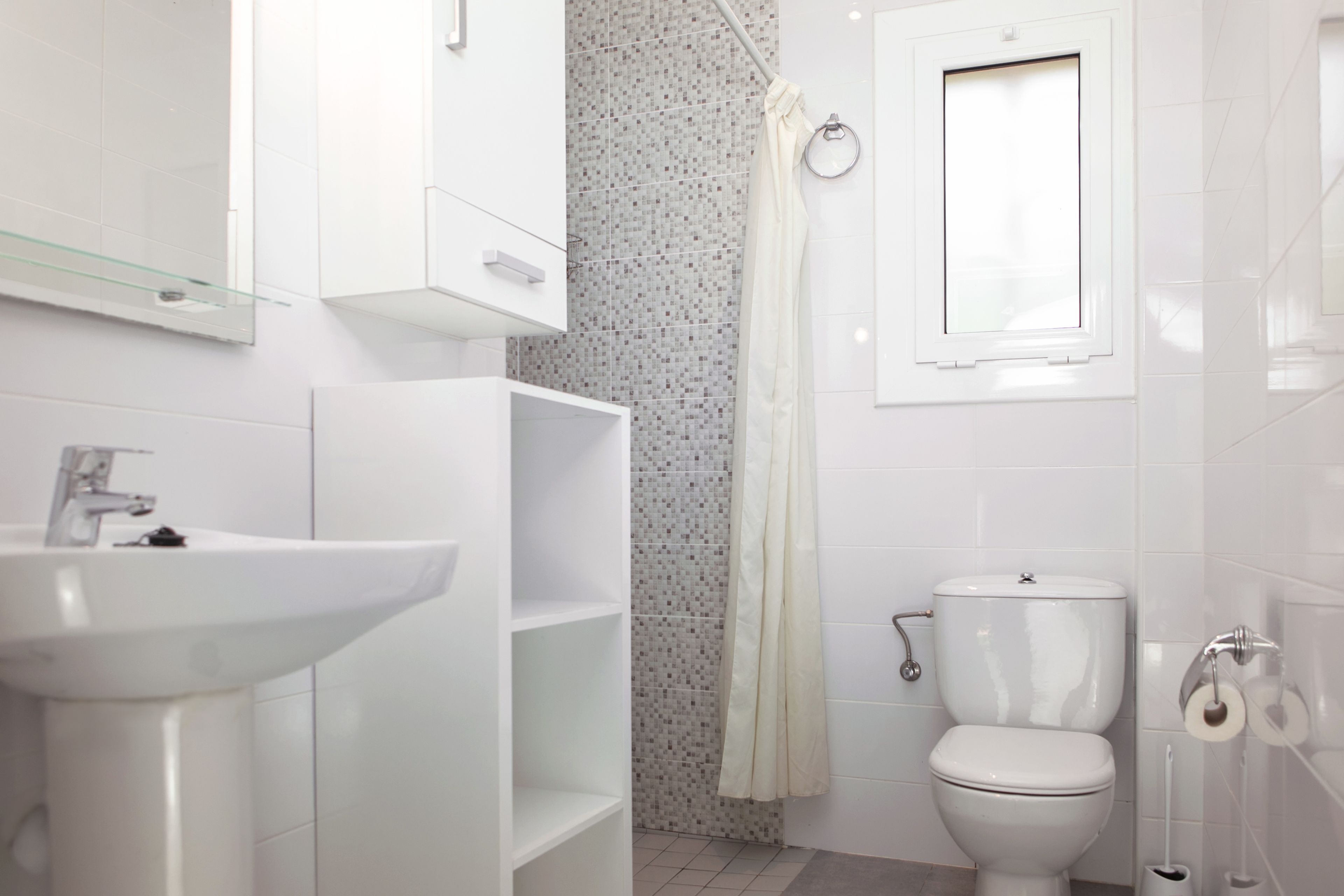 Un baño moderno con lavamanos, inodoro y cortina de ducha blancos.