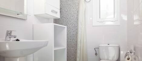 Une salle de bain moderne avec un lavabo blanc, des toilettes et un rideau de douche.