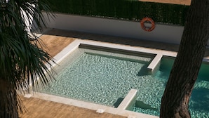 A rectangular pool with clear water, surrounded by a wooden deck and a green hedge. - RVApartaments Benelux (Castell-Platja d'Aro)