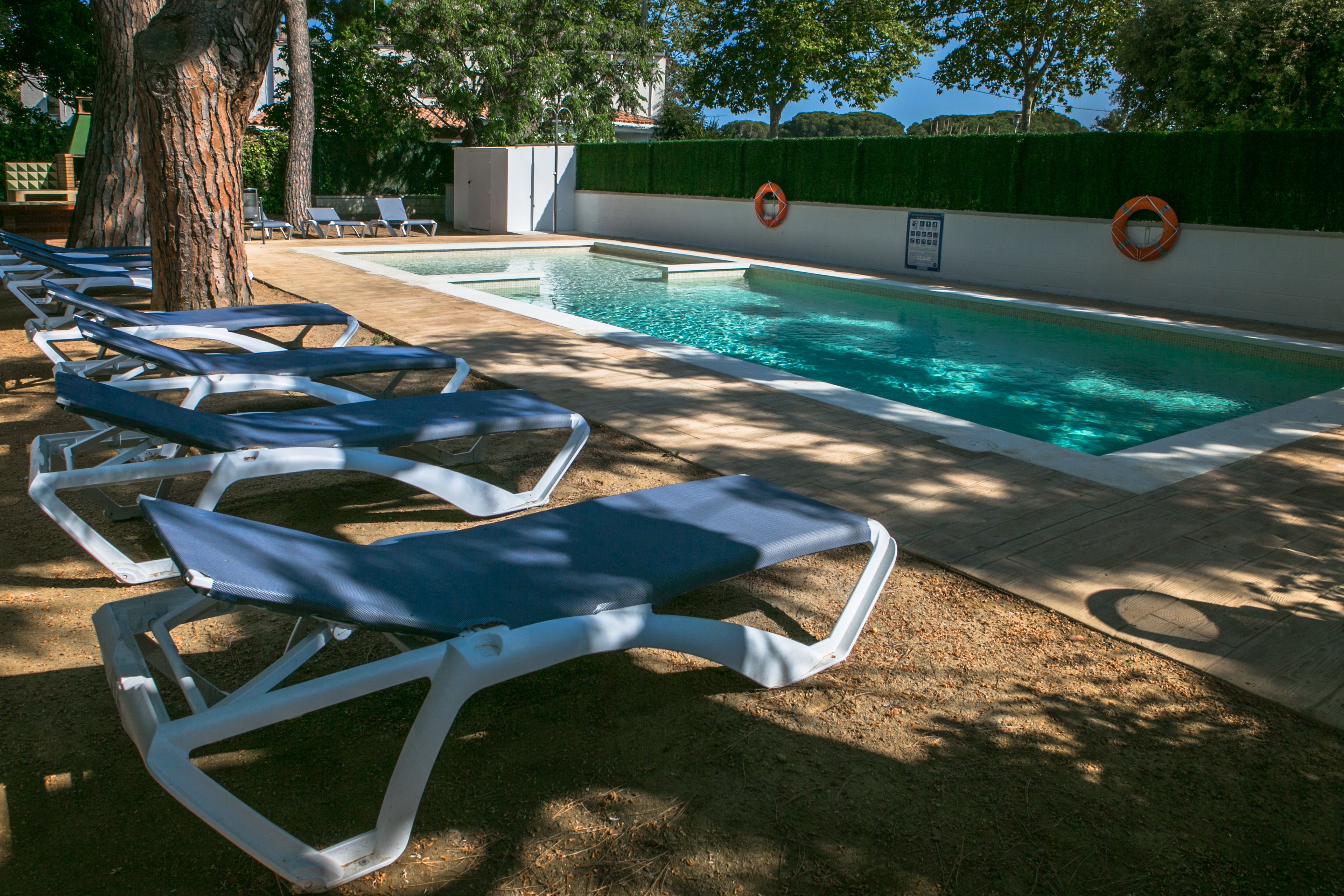 A swimming pool with lounge chairs and lifebuoys.