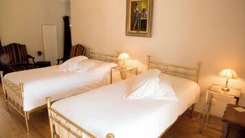 Two single beds with gold frames, white linens, and bedside lamps.