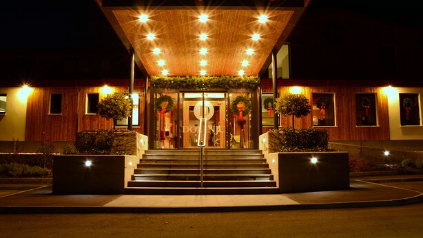 Un bâtiment moderne doté d’une façade en bois, d’une grande entrée vitrée et d’un hall d’entrée bien éclairé, accessible par un escalier.
