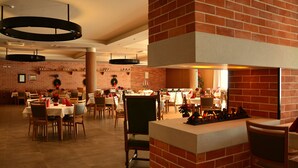 Un vaste espace dédié à la salle à manger, avec des murs en briques, de nombreuses tables et des chaises.