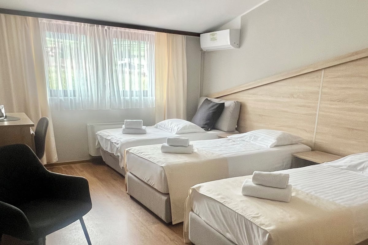 Habitación de hotel con tres camas, un escritorio y una silla.