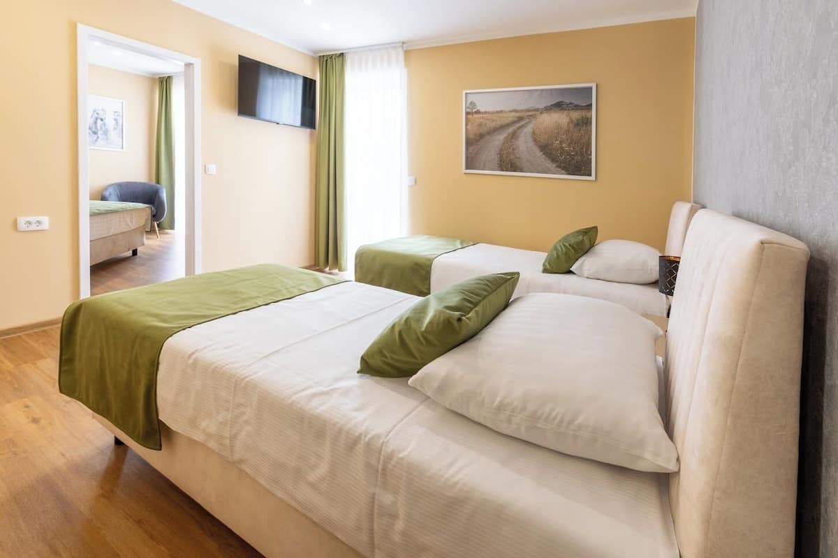 Habitación de hotel con dos camas, un televisor de pantalla plana, un cuadro y vistas a la carretera.