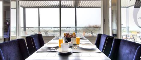 A dining area with a table set for breakfast, including plates, cups, and a bowl of fruit.