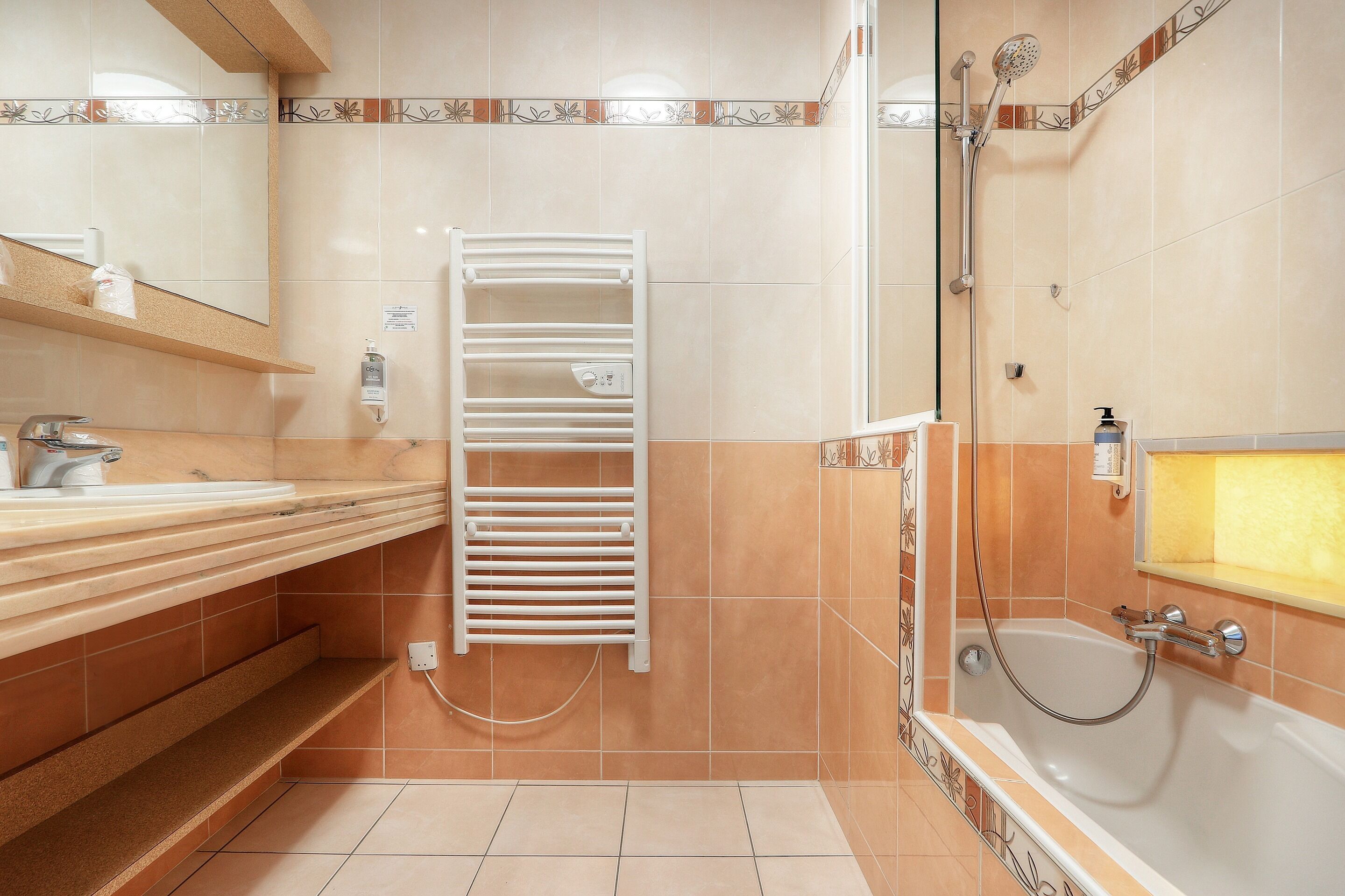 Ein Badezimmer mit einer Badewanne, einer Dusche, einem Handtuchhalter und einem Waschbecken.