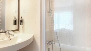 A bathroom with a sink, mirror, and shower.