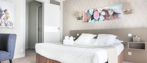 Una habitación de hotel con una cama, una silla, un estante en la pared y un cuadro.