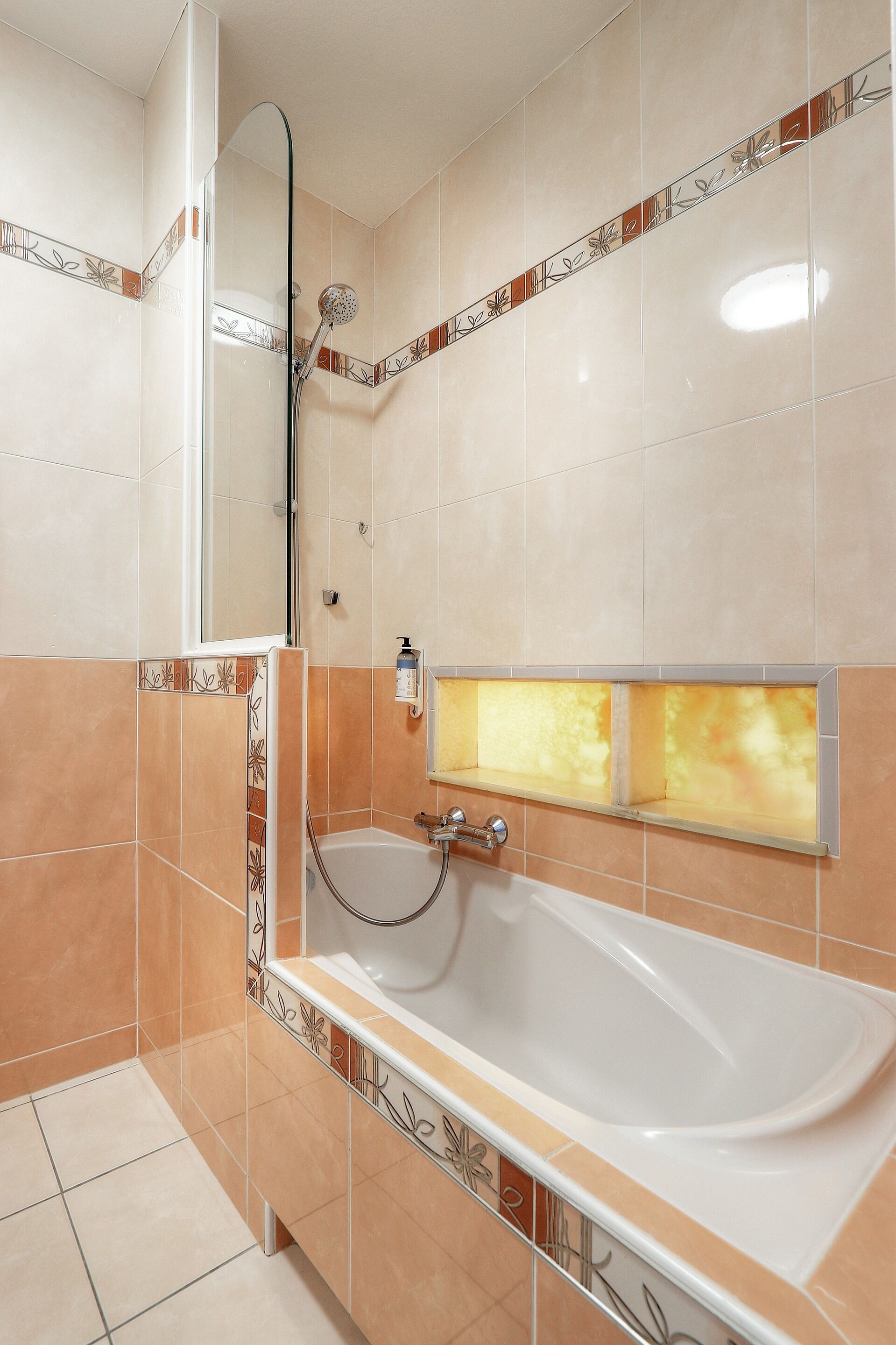 Een badkamer met een bad, douche en spiegel.