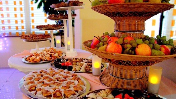 Una mesa de buffet con diversos alimentos y una cesta de frutas.