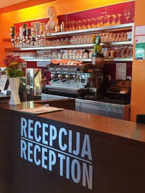 A bar area with a reception desk labeled "RECEPTION" and a coffee machine.