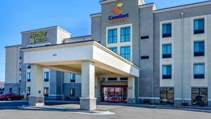 A hotel with a MainStay Suites and Comfort Suites sign, a covered entrance, and a parking lot with cars. - MainStay Suites Near Denver Downtown (Denver)