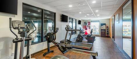 A gym with cardio machines, a weight bench, and a treadmill.