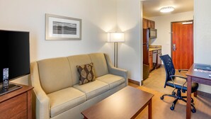 A hotel room with a sofa, a TV, a desk, and a chair. - MainStay Suites Near Denver Downtown (Denver)