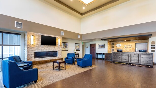 A spacious lobby with a stone fireplace, blue armchairs, a flat-screen TV, and a reception desk. - MainStay Suites Near Denver Downtown (Denver)