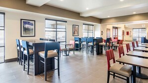 A spacious dining area with multiple tables and chairs, large windows, and framed artwork on the walls. - MainStay Suites Near Denver Downtown (Denver)