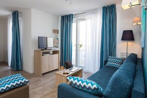 A modern living room with a sofa, coffee table, and a television on a wooden cabinet. - Maisonette in France with Modern Comfort (Noirmoutier en l'Ile)