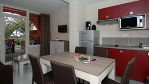 A compact kitchen with a microwave, refrigerator, and a dining area with a table and chairs.