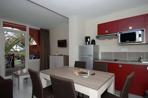 A compact kitchen with a microwave, refrigerator, and a dining area with a table and chairs.