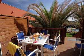 An outdoor patio with a table set for breakfast, surrounded by chairs, and a pool in the background. - Coastal Retreat w/ Balcony (LE CAP D'AGDE)
