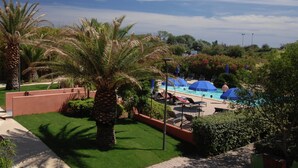 A pool area with umbrellas, palm trees, and a clear sky. - Cap d’Agde Retreat w/ Terrace (LE CAP D'AGDE)