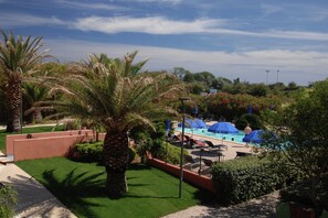 A pool area with umbrellas, palm trees, and a clear sky. - Cap d’Agde Retreat w/ Terrace (LE CAP D'AGDE)
