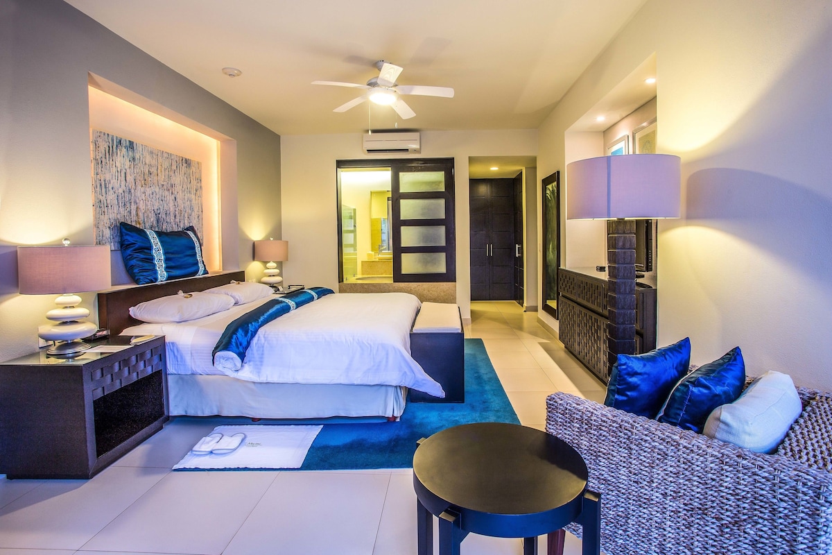 Una habitación de hotel moderna con cama, zona de estar y ventilador de techo.