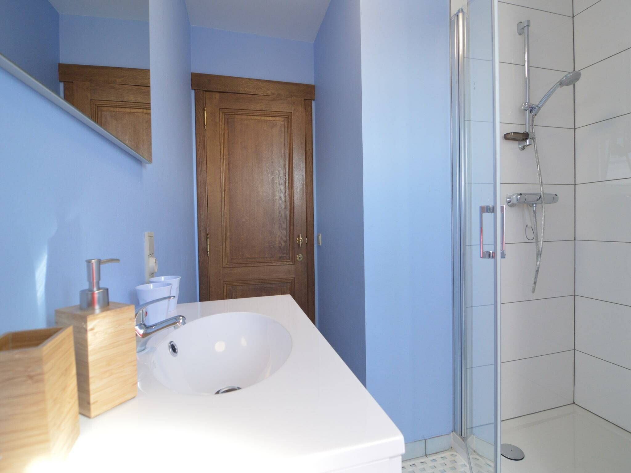 A bathroom with a white sink, wooden cabinets, and a glass shower enclosure.