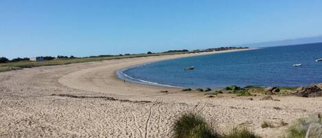 A sandy beach with a clear sky and calm sea.