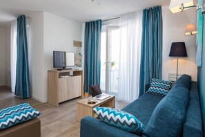 A modern living room with a sofa, coffee table, and a TV on a wooden stand. - Charming Stay by the Sea (Noirmoutier en l'Ile)