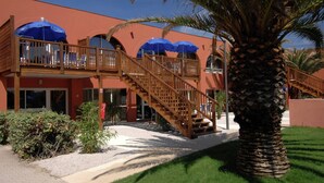 A hotel with a red exterior, wooden balconies, and blue umbrellas. - Apartment near beach in lively resort (LE CAP D'AGDE)