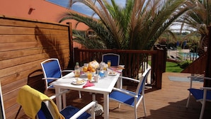An outdoor patio with a table set for breakfast, surrounded by chairs, and a pool in the background. - Apartment near beach in lively resort (LE CAP D'AGDE)
