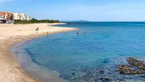 A beach with clear water, a sandy shore, and buildings in the background. - Apartment near beach in lively resort (LE CAP D'AGDE)