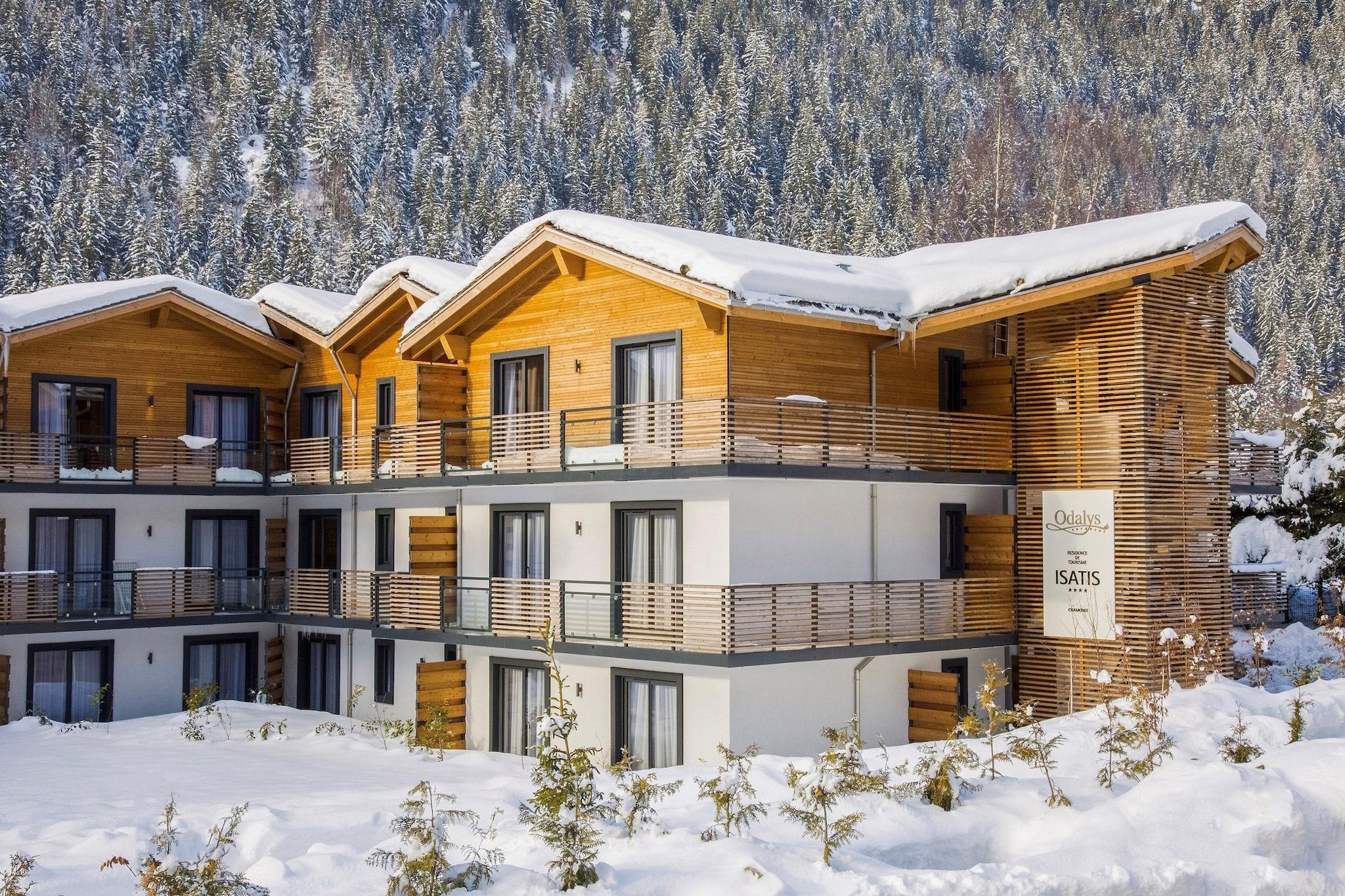 Un edificio de madera de varios pisos con balcones, rodeado de árboles cubiertos de nieve.