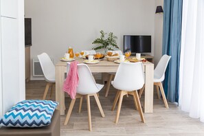 Ein moderner Essbereich mit Holztisch, weißen Stühlen und einem Fernseher.
