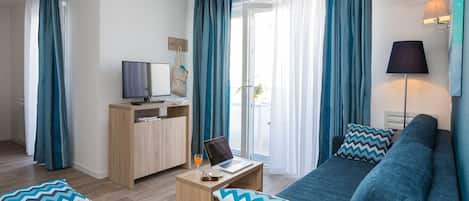 Una sala de estar moderna con un sofá, una mesa de centro y un televisor sobre un mueble de madera.