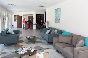 A modern living room with sofas, a coffee table, and a reception desk.