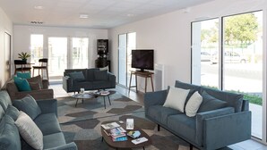 Un salon moderne avec un ensemble de canapés, une table basse avec des magazines et un téléviseur posé sur un meuble.