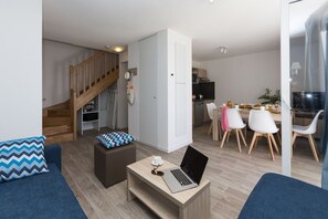 Un salon moderne avec un canapé, un pouf et une table basse sur laquelle se trouve un ordinateur portable.