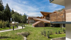 Een modern gebouw met een schuin dak, omringd door een verzorgd gazon en een berg op de achtergrond.