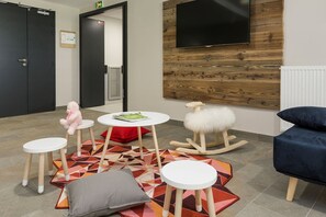 A modern waiting area with a wooden wall, a mounted TV, and a colorful geometric rug.