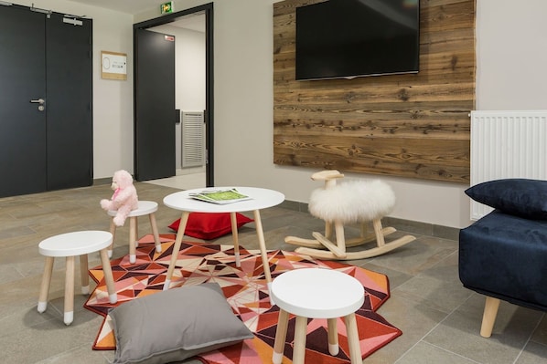 A modern waiting area with a wooden wall, a mounted TV, and a colorful geometric rug.